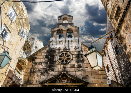 Des nuages sombres derrière une petite, vieille église en pierre avec plusieurs cloches au tour c'est dans la vieille ville de Dubrovnik en Croatie. Banque D'Images