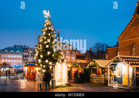 Riga, Lettonie. Marché de Noël sur la place du Dôme. Arbre de Noël et de maisons de commerce. Célèbre en hiver Soir Nuit à l'éclairage de fête Illuminations Banque D'Images