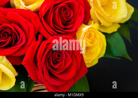 Partie d'un bouquet de roses rouges et jaunes dans un panier de près. Banque D'Images
