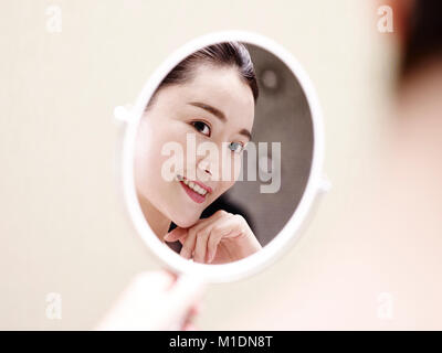 Belle jeune femme asiatique se voir en miroir, heureux et souriant. Banque D'Images