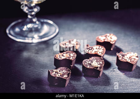 Le chocolat en forme de cœur tombe dans un verre de brandy l'horizontale Banque D'Images