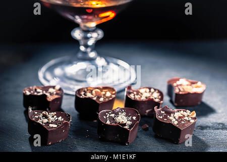 Le chocolat en forme de cœur tombe dans un verre de brandy l'horizontale Banque D'Images