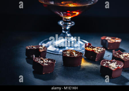 Le chocolat en forme de cœur tombe dans un verre de brandy l'horizontale Banque D'Images