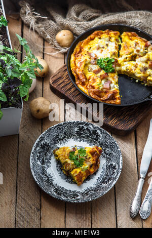 Omelette au bacon, pommes de terre, poireaux et fromage sur un plat, vue du dessus Banque D'Images