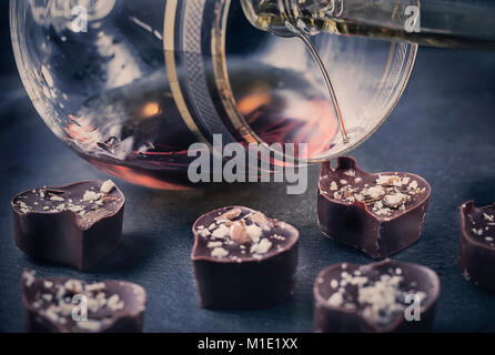 Le chocolat en forme de cœur tombe dans un verre de brandy focus sélectionné Banque D'Images