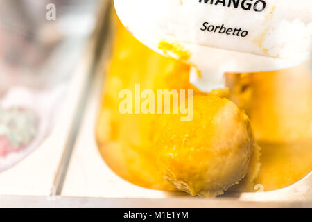 Gros plan macro de saveur mangue sorbet orange jaune crème glacée à signer sur l'affichage en magasin cafe shop avec écope en Italie, l'Italien sorbetto Banque D'Images