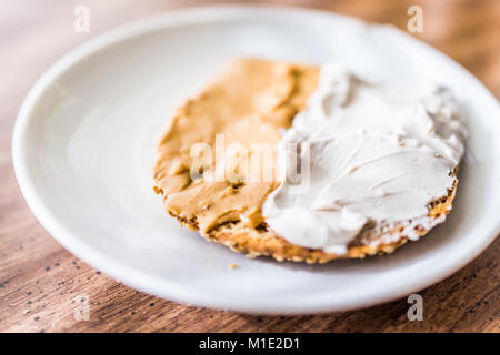 Gros plan du morceau de coupe le blé entier grillé sur pain de grains germés avec plaque de crème blanche fromage à tartiner sur la table macro, le beurre d'arachide Banque D'Images