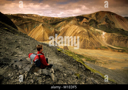 L'Islande. Landmannalaugar Parc National. Touriste, randonneur, woman on rocky hill, appréciant la vue. Banque D'Images