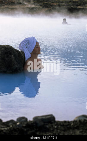 L'Islande. 73320. Bains naturels de Myvatn. Femme portant un masque de beauté, une serviette sur la tête, assis dans spa géothermique. Banque D'Images