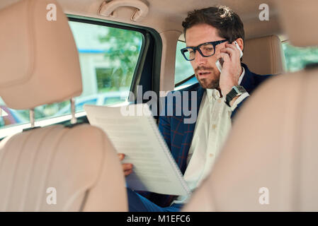 Homme d'affaires travaillant dans le siège arrière d'une voiture Banque D'Images