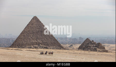 Camel riders en face de l'Menkaourê pyramide de Gizeh à l'horizon du Caire dans le derrière du smog Banque D'Images