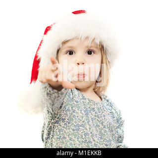 Petit Enfant dans Santa Hat le doigt sur le point blanc. Vous m'a acheté un cadeau ? Je veux que cette chose ! Banque D'Images