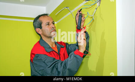 Électricien installe dans le nouvel appartement. Branchement d'une prise à une boîte électrique. Banque D'Images