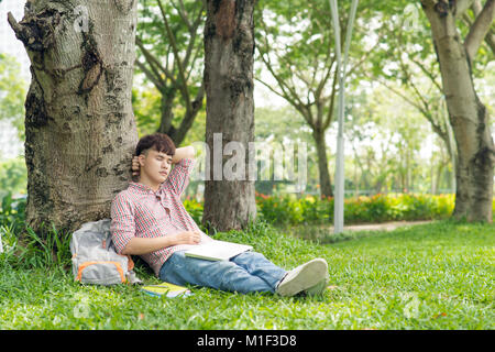 Jeune étudiant, man smiling while lying on grass Banque D'Images