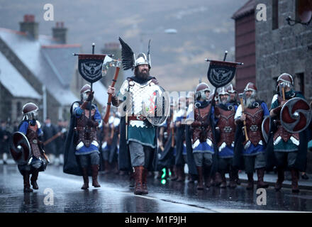 Les membres de l'équipe de Jarl vêtus de costumes Viking marche dans les rues de Lerwick sur les îles Shetland pendant le Festival Up Helly Aa Viking. Banque D'Images