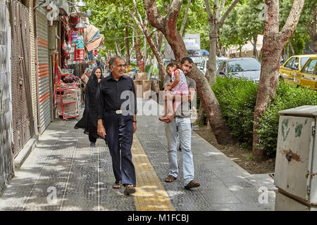 Isfahan, Iran - avril 24, 2017 : un homme marche dans la rue et porte sa fille dans ses bras, il y a des personnes qui se trouvent à proximité. Banque D'Images