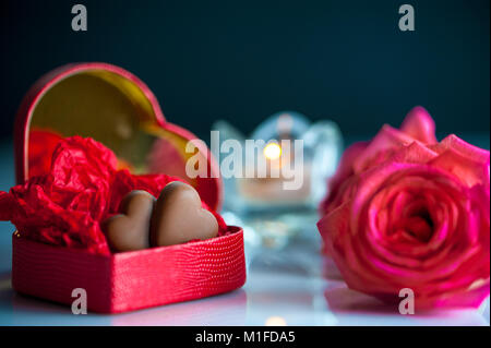 Macro image de red heart-shaped box coeurs chocolat wit , rose des fleurs et une bougie. focus sélectif. Banque D'Images