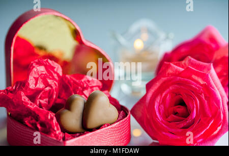 Macro image de red heart-shaped box coeurs chocolat wit , rose des fleurs et une bougie. focus sélectif. Banque D'Images