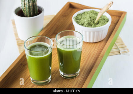 Deux coups d'agropyre avec de la poudre de wheatgrass et cuillère en bois Banque D'Images