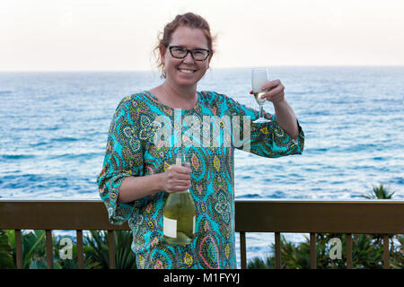 Ginger femme d'une quarantaine d'années par la station, drinking champagne Banque D'Images