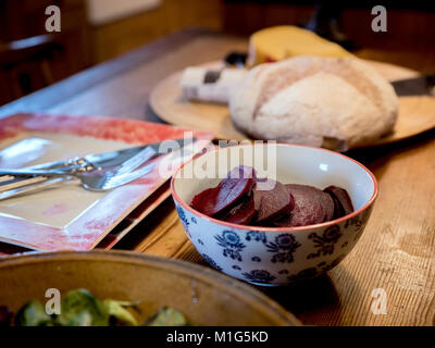 Une table de cuisine de ferme avec du pain, du fromage et de la salade pour le déjeuner. Banque D'Images