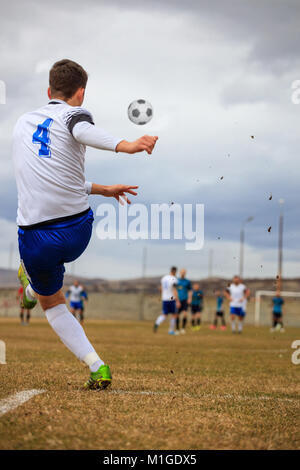 Joueur de football sur arena kicks le ballon au cours de match de football. L'équipe de flou, ciel en toile de fond, derrière photo Banque D'Images