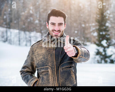 Young man smiling, faisant thumb up signe avec sa main puis à deux mains Banque D'Images