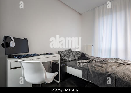 Chambre avec lit simple, un bureau et une chaise blanche Banque D'Images