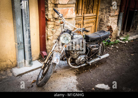 Une vieille moto se tient près de l'entrée de la vieille maison. Banque D'Images