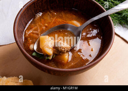 Vue rapprochée de la plaque d'argile et une cuillère à soupe de betteraves rouges ou borsch. Le bortsch ukrainien soupe à la tomate sur fond de bois. Banque D'Images