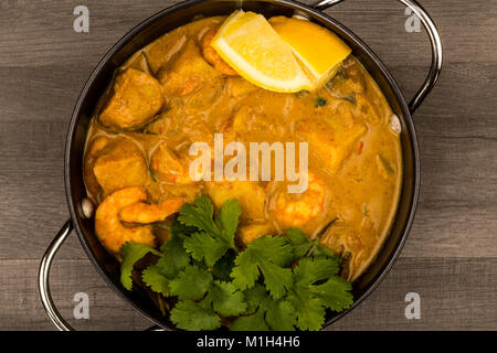 Sri Lanka King Style Gambas au curry avec du citron et de la coriandre herbes sur une table en bois foncé Banque D'Images