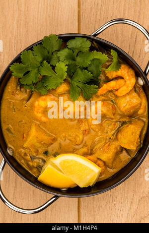 Sri Lanka King Style Gambas au curry avec du citron et de la coriandre herbes sur une table en bois clair Banque D'Images