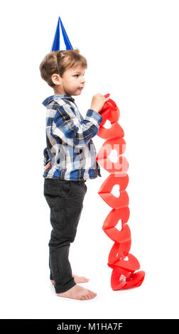 Cute little boy in birthday hat holding paper guirlande de coeurs rouges sur fond blanc Banque D'Images