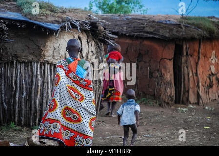 Le Parc National de Masai Mara, Kenya 4 novembre 2008 .les femmes masaï à pied en face de maisons traditionnelles.en arrière-plan les femmes masaï portant leurs enfants sur le Banque D'Images