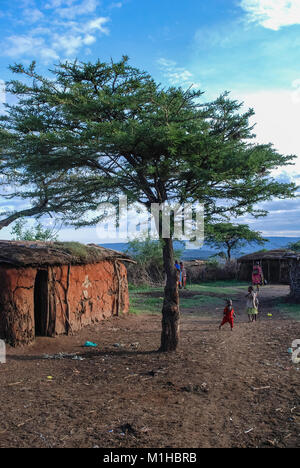 Le Parc National de Masai Mara, Kenya 4 Novembre 2008.Masai village. Dans l'arrière-plan il y a des femmes avec enfants, maison et clôture du village. Banque D'Images