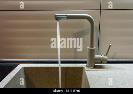 Close up nouveau robinet métal jaune dans une cuisine. Banque D'Images