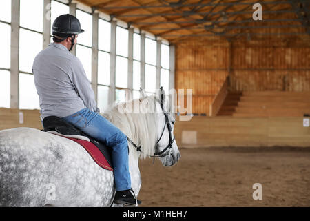 Les gens sur un cheval de la formation dans une arène en bois Banque D'Images