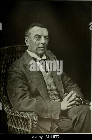 Noir et blanc, trois-quarts, portrait photographique de l'état Anglais Joseph Chamberlain, assis dans un fauteuil en osier, avec ses mains et jambes croisées, portant un monocle, un costume et cravate avec gilet, et une montre sur une chaîne, à partir du volume "l'Americana : une bibliothèque de référence universelle, comprenant les arts et les sciences, la littérature, l'histoire, biographie, géographie, du commerce, etc. du monde, ' Écrit par Frederick Converse Beach et George Edwin Rines, 1903. Avec la permission de Internet Archive. () Banque D'Images