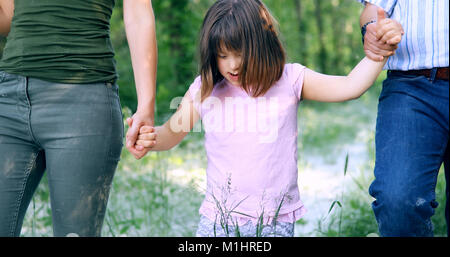 Belle petite fille avec le syndrome de marcher avec les parents Banque D'Images