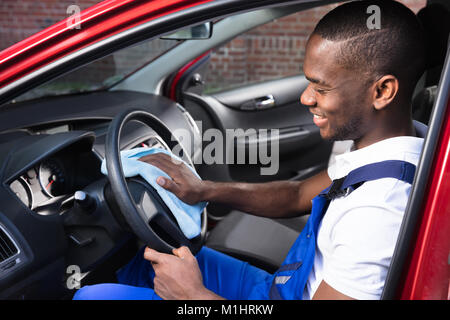 Heureux Travailleur Homme volant de nettoyage de voiture avec tissu bleu Banque D'Images