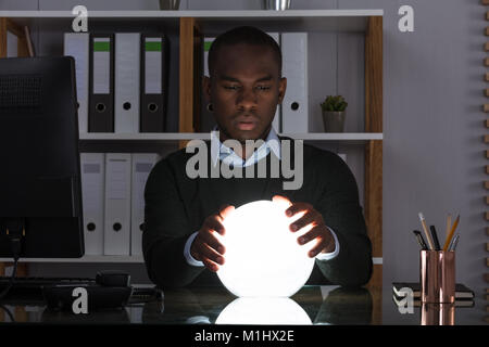 Portrait of African Businessman prédire avec boule de cristal sur 24 At Office Banque D'Images