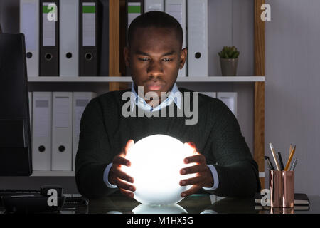 Portrait of African Businessman prédire avec boule de cristal sur 24 At Office Banque D'Images