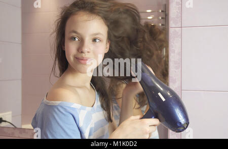 Belle teen girl sèche cheveux sèche-cheveux dans la salle de bains Banque D'Images
