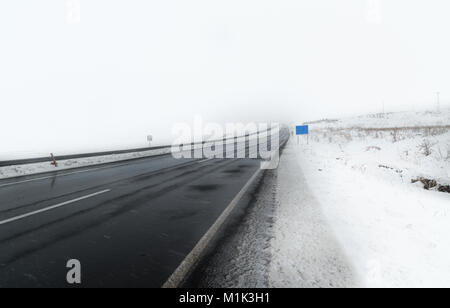 Snowy route asphaltée, les véhicules allant à la card Banque D'Images