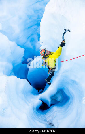 Grimpeur sur glace dans la région de Yellow Jacket escalade d'un grand moulin avec de multiples tunnels verticaux sur le Glacier Spencer en Alaska. Banque D'Images