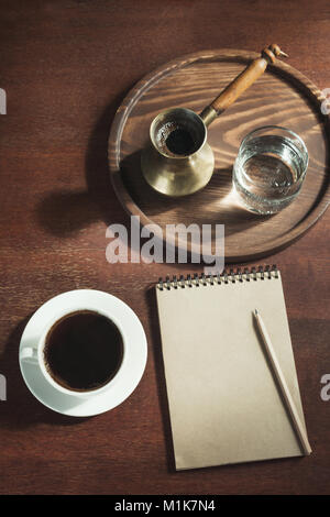 Tasse de café noir avec du cuivre et du verre dans l'eau cezve vintage style. Vue de dessus. Matin éditeur ou blogger. Banque D'Images