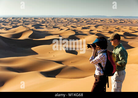 Le Maroc, Mhamid, Erg Chigaga dunes de sable. Désert du Sahara. Deux touristes sur les dunes de sable de la photographie. Banque D'Images