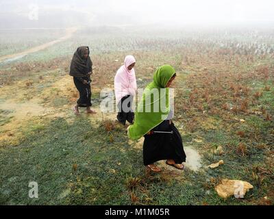 16 janvier 2018 - Cox's Bazar, Bangladesh - femmes réfugiés rohingyas vu marcher à travers un champ sous la pluie.Même le Pape François n'a pas été autorisé à dire un mot '''' des rohingyas en Birmanie. Plus d'un million de réfugiés rohingyas qui ont été forcés de s'enfuit de l'État de Rakhine au Myanmar en août 2017 pour sauver leur vie de nettoyage ethnique vivent dans des conditions très de base dans les camps de réfugiés au Bangladesh et leur avenir est très incertain. Ils ont peur de rentrer chez eux - mais traité de rapatriement a été déjà signé pour les renvoyer dans leur pays où ils ne sont pas acceptés. (Crédit Image : © Banque D'Images