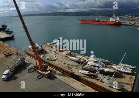 Les membres de l'Ouragan Maria FSE-10 transition vaisseaux touchés de l'équipe d'intervention d'une barge pour être transportés à des fins d'élimination dans le port de Ponce, Puerto Rico, le 26 janvier 2018. L'équipe était composée de membres de la Garde côtière et les équipes de sauvetage locales, travaillant dans le FSE-10 suppriment les bateaux qui étaient coincés dans l'ouragan. Le FSE-10 offre pas de frais, options pour enlever ces navires ; les propriétaires de bateaux concernés sont priés d'appeler la hotline de sensibilisation des propriétaires de navire au (786) 521-3900. (U.S. Photo de la Garde côtière du Maître de 2e classe Lara Davis) Banque D'Images