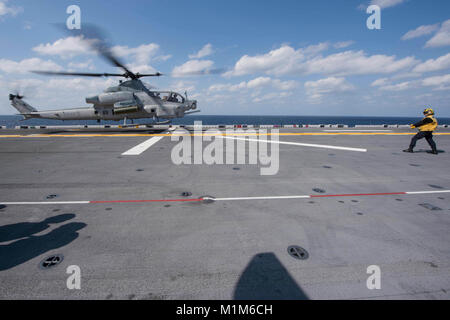 180130-N-NB544-097 MER DES PHILIPPINES (janv. 30, 2018) l'Aviation maître de Manœuvre (manipulation), 3ème classe Allison Bilbrey de Fort Walton, en Floride, des signaux à la pilote d'un hélicoptère AH-1Z Viper affecté à l 'Gunfighters' de l'hélicoptère d'attaque léger Marine HMLA (Escadron) 369, tel qu'il atterrit sur le pont d'envol du navire d'assaut amphibie USS Bonhomme Richard (DG 6). Bonhomme Richard fonctionne en Indo-Asia-région du Pacifique dans le cadre d'une patrouille régulière et offre une capacité d'intervention rapide en cas de catastrophe naturelle ou d'urgence régionaux. (U.S. Photo par Marine Communications de Masse Banque D'Images
